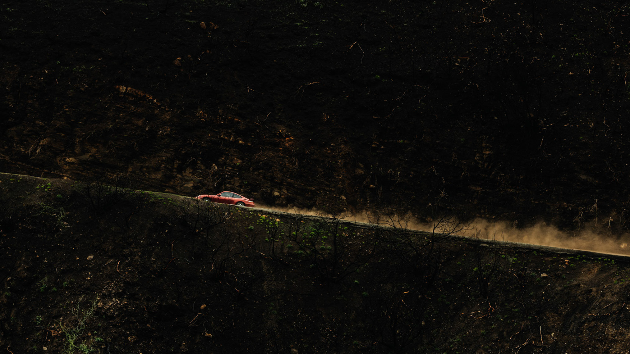 Red exotic car driving up a hill